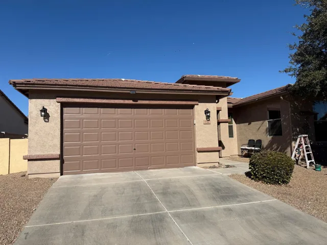 Brown garage door with coordinated trim on a light stucco home