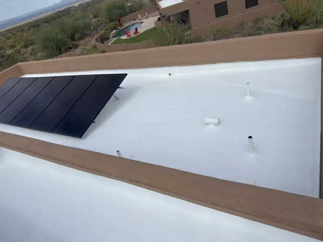 White roof finish bordered by tan parapet walls beside solar panels