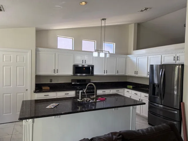 White kitchen cabinets and island contrasted with dark countertops