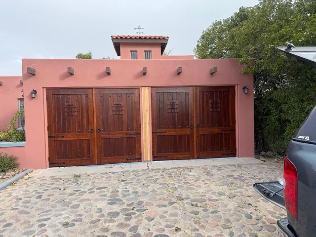 Wood-paneled garage doors set into a terracotta-colored house exterior